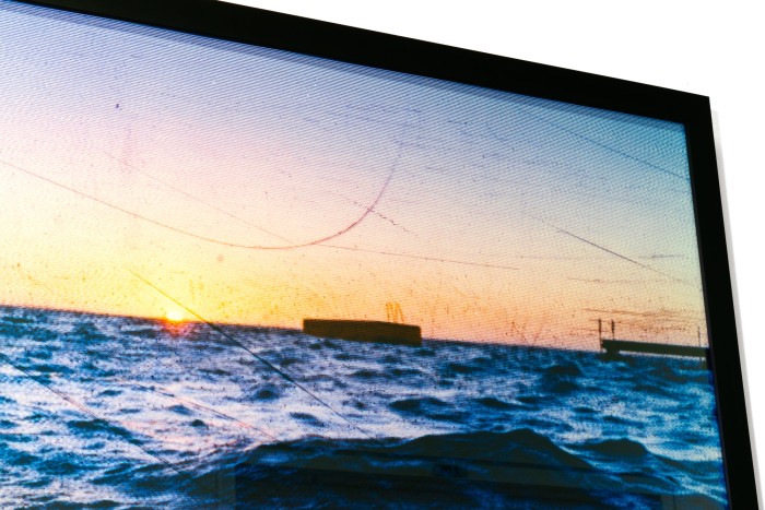 A framed photo of the sea at sunset with a jetty and pontoon in the water