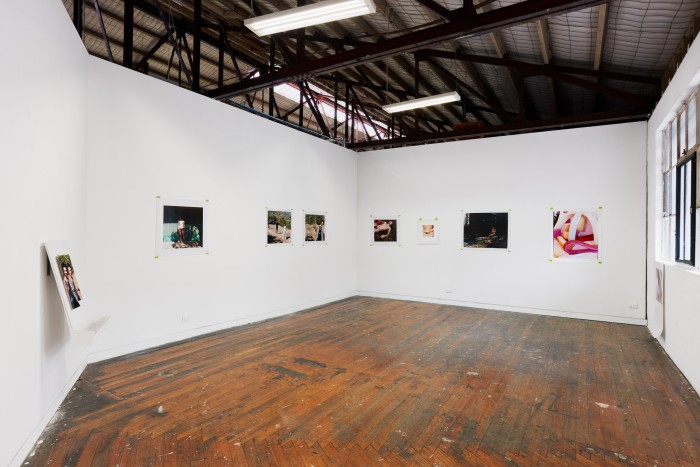 A wide angle photograph of photographs hanging on two walls. The photographs are portraits and still lives.