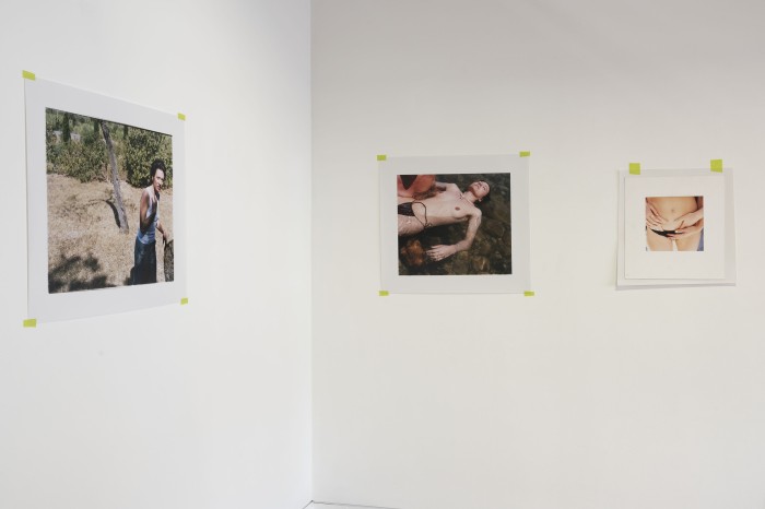 photograph of three printed photos taped to a wall with green masking tape. The photographs depict a person in the ocean, standing on grass and a close up of hands in someone's undies