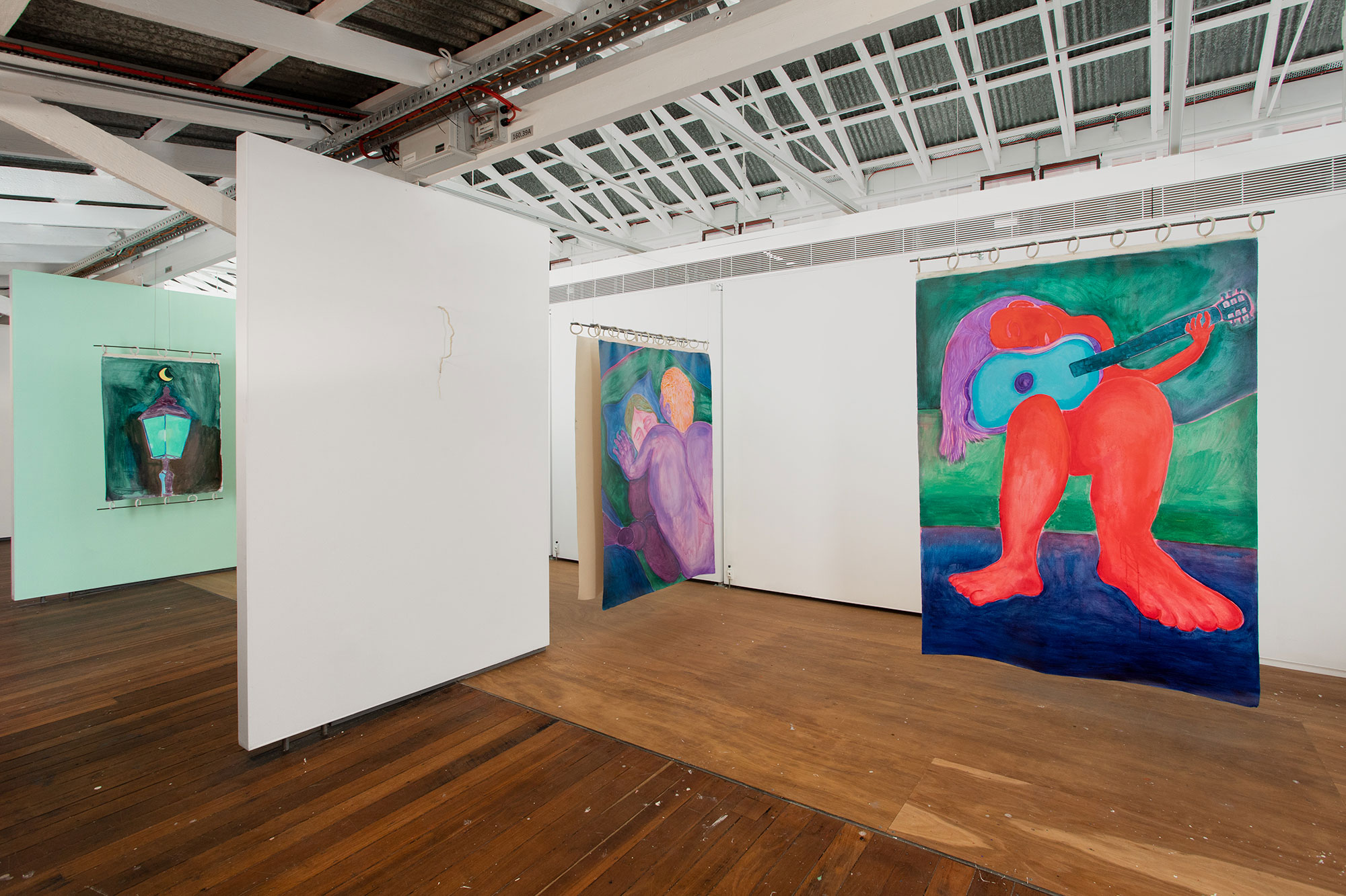 a collection of paintings are installed across a large space of walls. there are figure intertwined and one wall is painted green