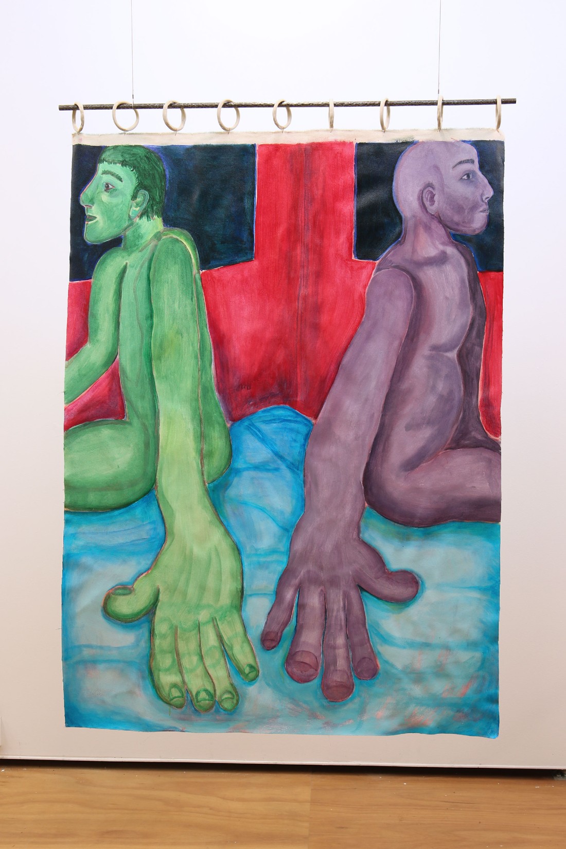 a painting of a green figure sits facing away from a purple figure on a blue bed, there are red walls and dark windows. Their hands are huge in the front of the composition, this painting hangs from ceramic rings and a pole like a curtain