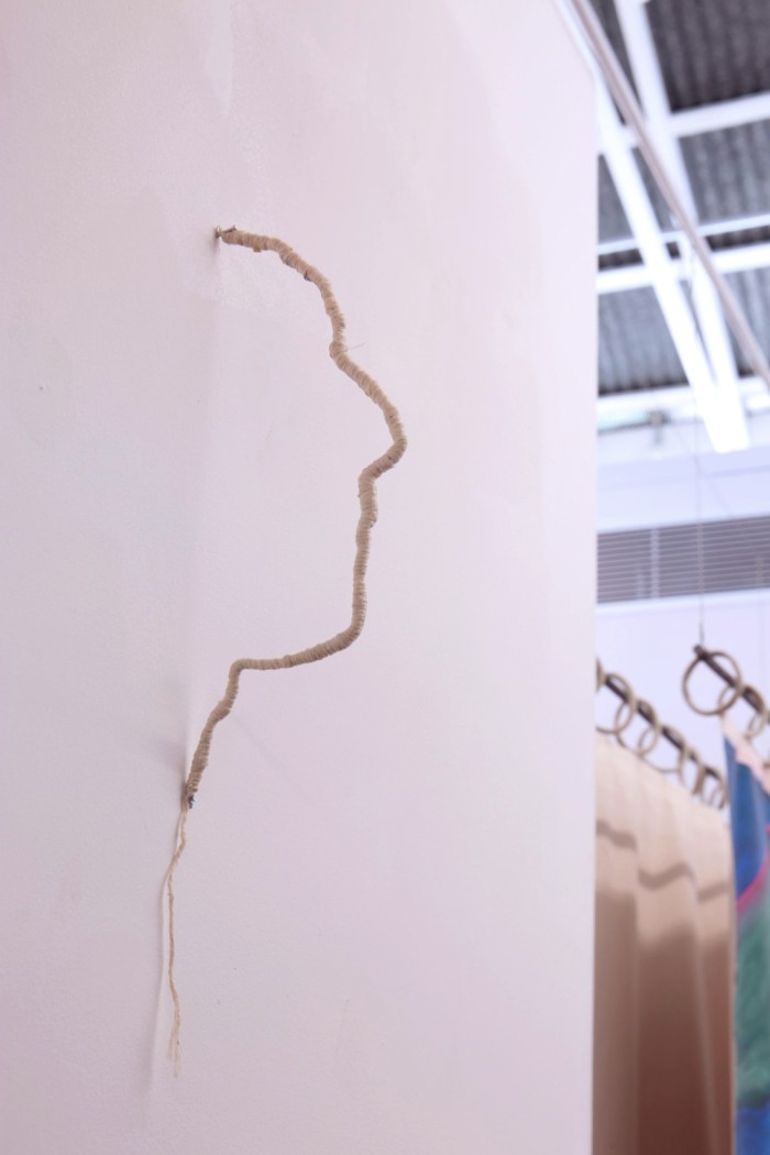 a silhoutte of a side profile is sculpturally installed coming out of a wall as a thin, 3D line made of string