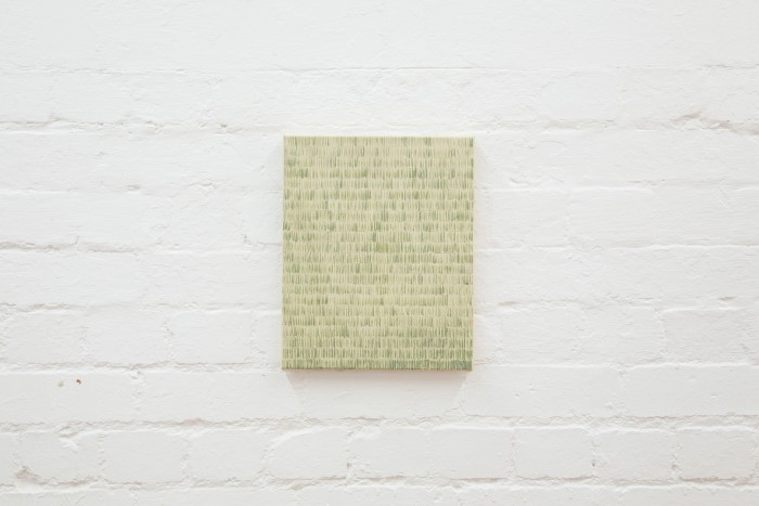 small portrait painting on white brick wall. Short green vertical lines repeated in rows to fill whole canvas.
