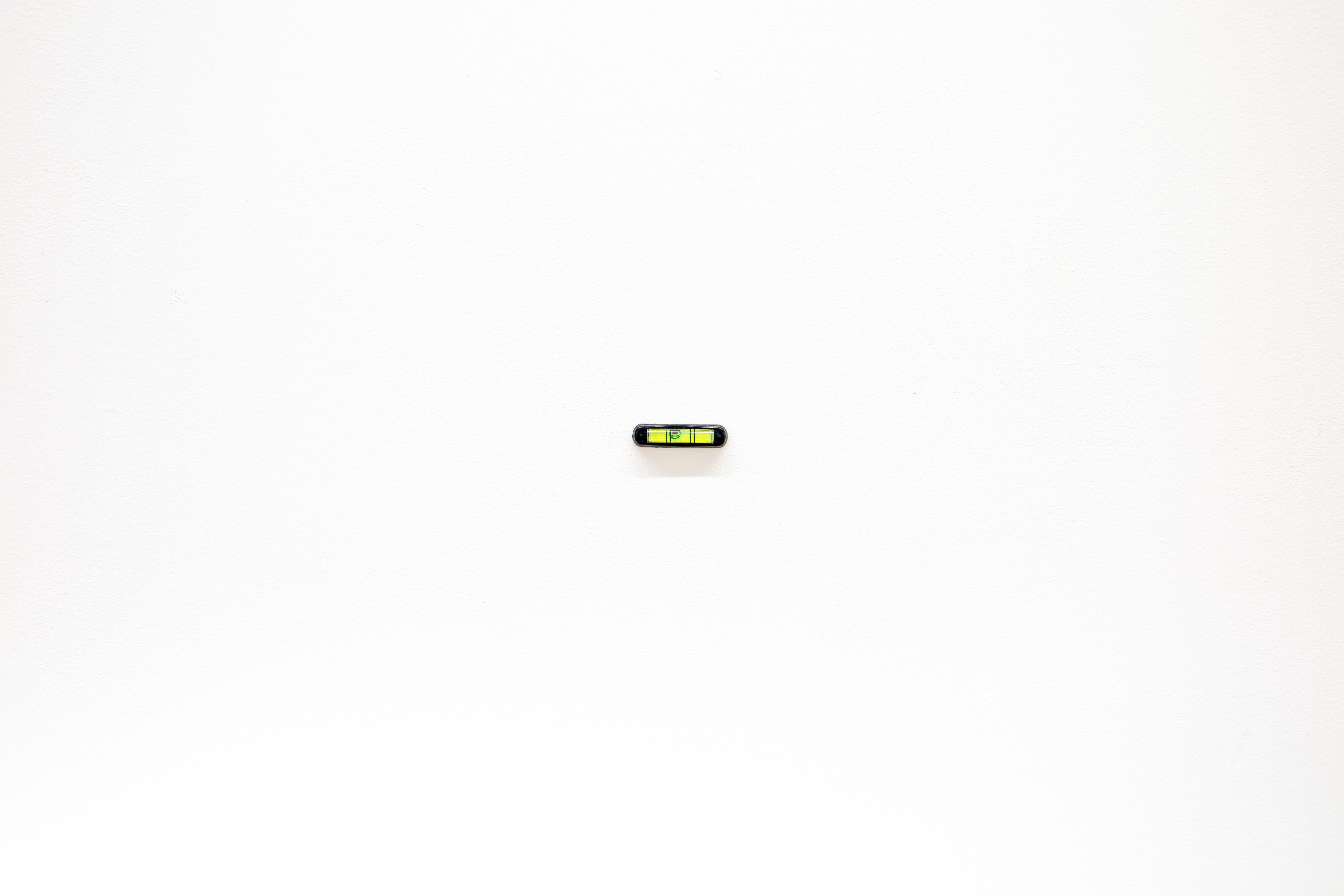 A spirit level is hung on a wall slightly askew